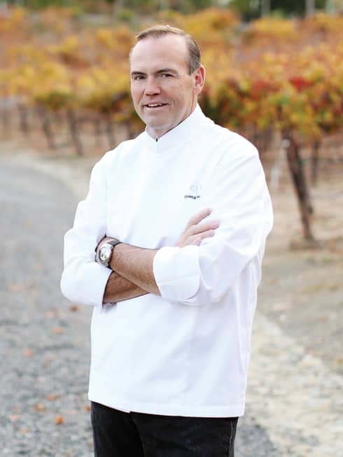 Portrait photo of Executive Chef Charlie Palmer wearing uniform, on path