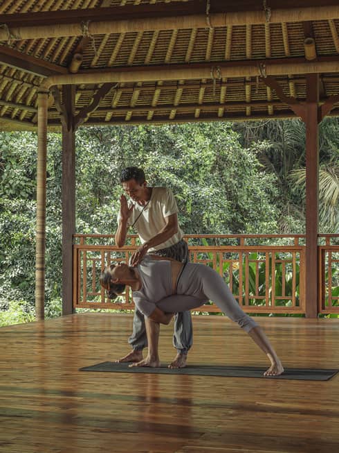 Instructor guides guests into yoga pose in outdoor pavilion