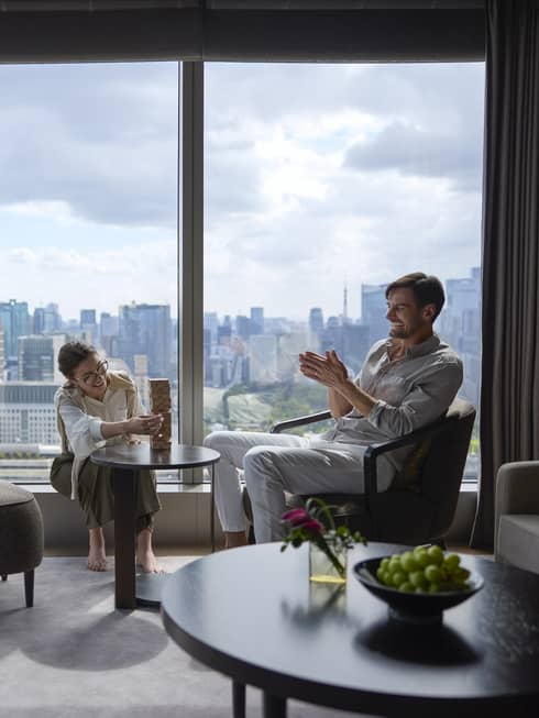 Couple enjoying a relaxing moment in a luxury suite at Four Seasons Hotel Tokyo at Otemachi with city views.