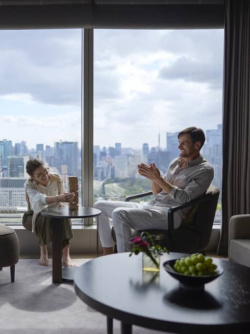 Couple enjoying a relaxing moment in a luxury suite at Four Seasons Hotel Tokyo at Otemachi with city views.