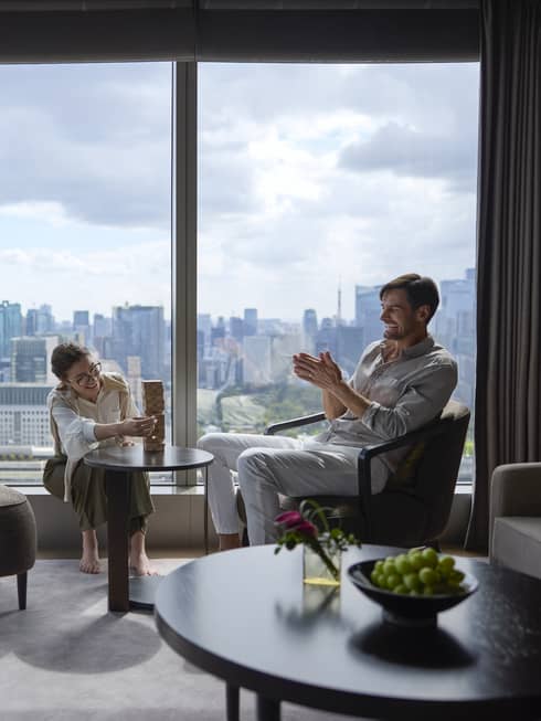 Couple enjoying a relaxing moment in a luxury suite at Four Seasons Hotel Tokyo at Otemachi with city views.