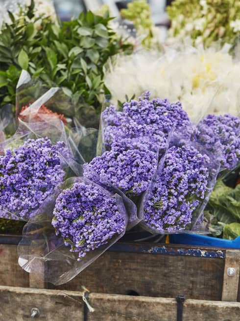 Close up of bouquets or purple, white and green flowers in the back of a wooden wagon