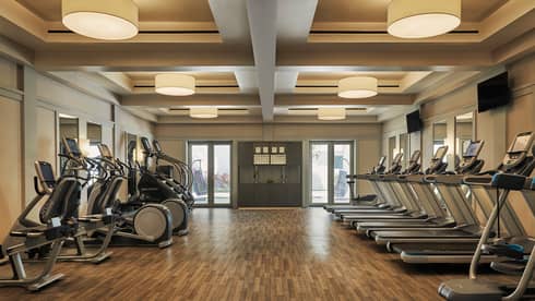 A well lit gym with cardio machines.