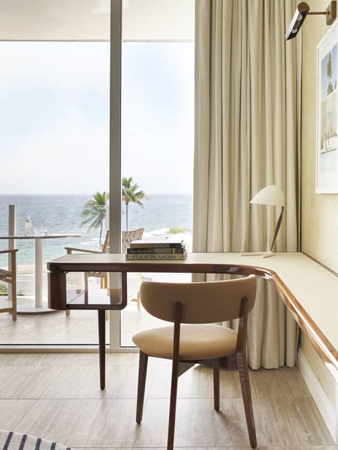 A workspace featuring a desk and chair, with a large window revealing a beautiful ocean view.