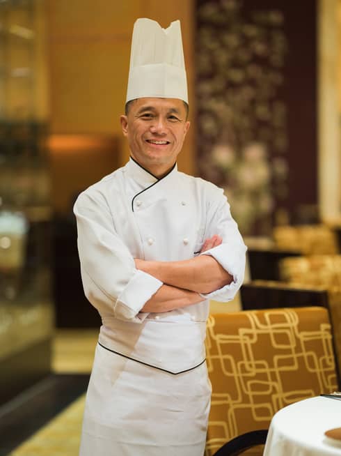 Portrait photo of Chinese Kitchen Executive Chef Cheung Chi Choi wearing white uniform, tall hat
