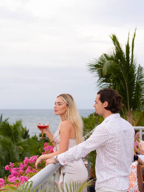 Man and woman enjoy a cocktail on rooftop lounge in tropical location, with ocean view