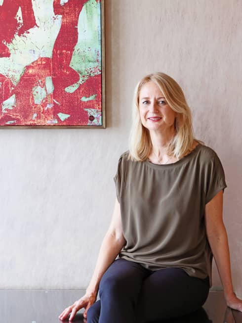 Kate Whitehead, a TRE specialist at Four Seasons Hong Kong, sits on a chair with artwork hanging on a wall
