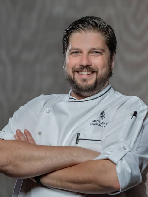 Chef Martin Morelli smiles and crosses him arms as he posed for a photo