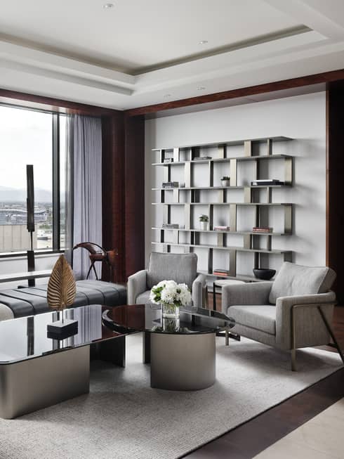 Contemporary living room with plush l-shaped sofa, wall of shelves, windows