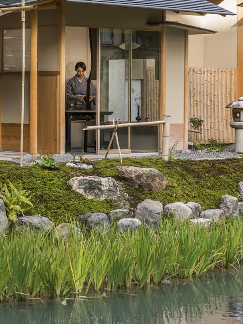 Rock garden, fountain in front of Shakusui tei building, woman in robe behind window