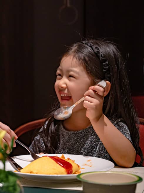 Smiling young girl and her dad dig into omurice topped with ketchup