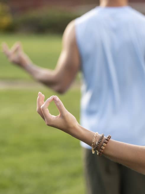 A man and woman doing yoga outside.