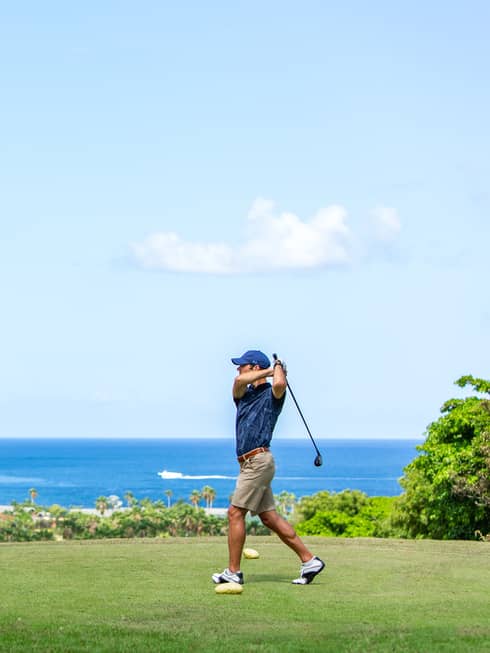 A man golfing near an ocean.