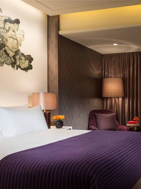 Hotel room bed with purple blanket under black-and-white Chinese brushwork mural