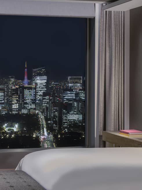 Hotel room with wall of windows looking out to city at nighttime