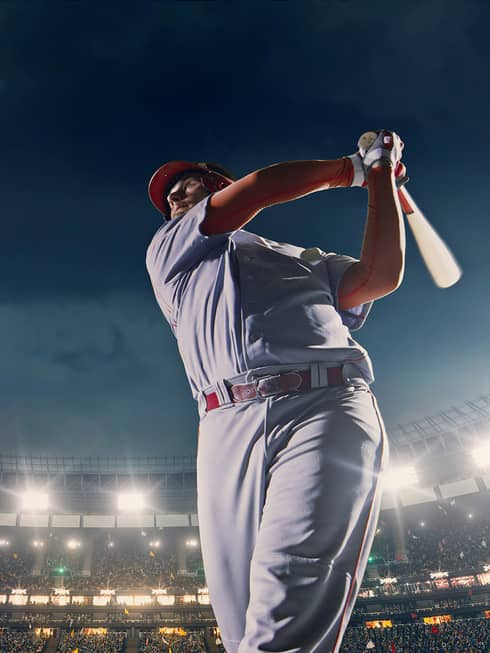 Up-close image of a baseball player swinging a bat in a full stadium at night