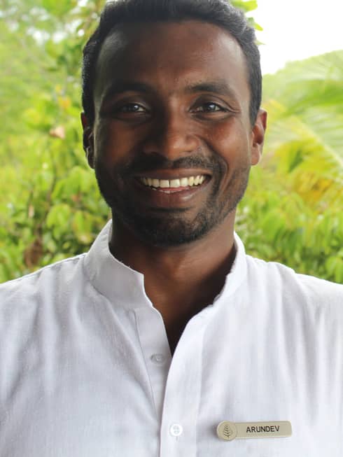 Portrait of yogi and fitness instructor Arun Dev smiling, wearing white uniform