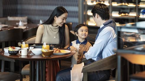 Parents and a child sitting at a dining table enjoying breakfast together