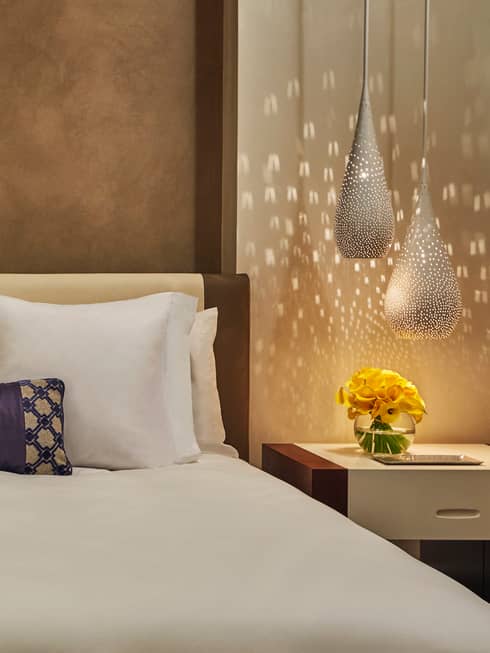 Reflection of light from teardrop lamps on wall beside bed
