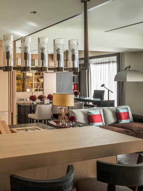 Corner of kitchen with light wood floor-to-ceiling cabinets, island under chandelier