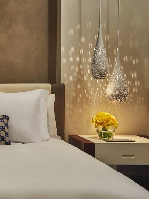 Reflection of light from teardrop lamps on wall beside bed