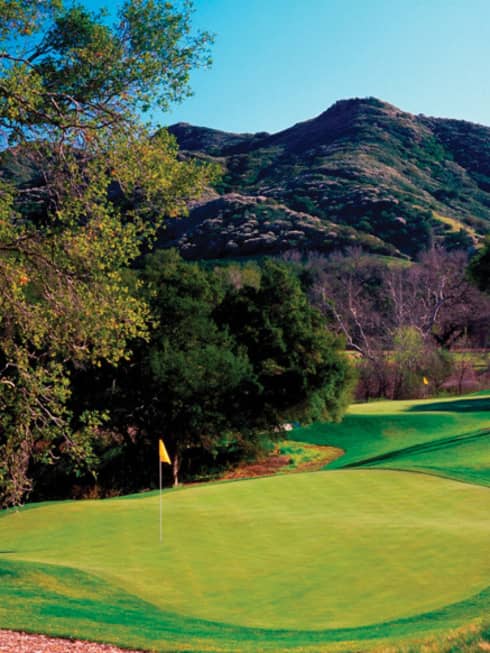 A golf course with a beautiful mountain in the background.