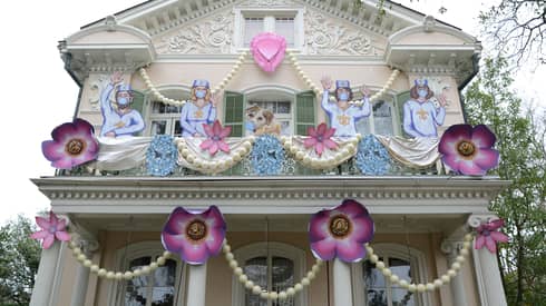 Cream-coloured Gothic two-storey house in New Orleans with pink flower garland and Mardi Gras decorations