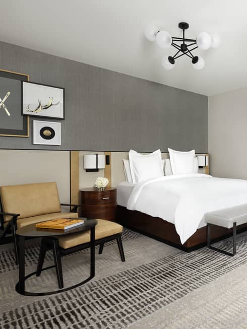 Fireplace, hotel bed and armchair in modern bedroom suite