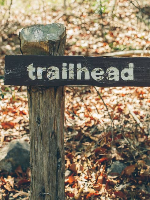 A wooden sign points in the direction of the trailhead at the Wild Basin Preserve