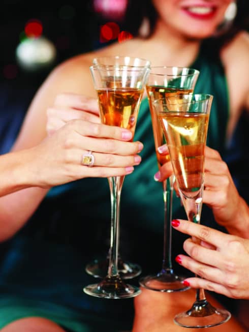 Close-up of women in evening gowns toasting with glasses of Champagne