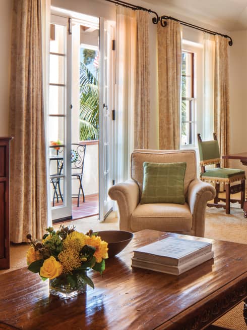 Sunny dining and seating area with open patio door, plush armchairs, wood table
