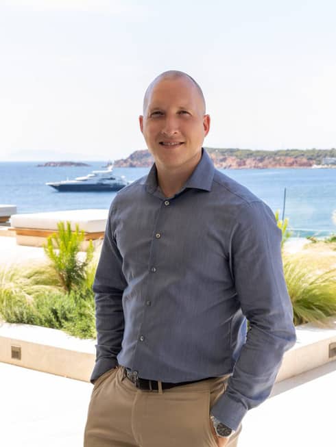 Michael Gunnar Eberhardt standing in front of the sea as a yacht drifts by.