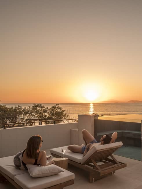 Couple relaxes on plush lounge chairs on Nafsika One Bedroom Terrace Suite with Pool deck