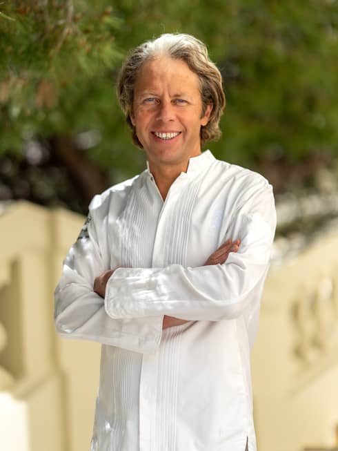 A chef in a white shirt standing in an outdoor setting