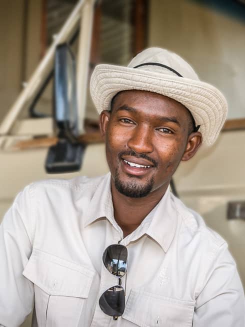 Portrait photo of safari driver-guide Isack Munyangabe wearing hat