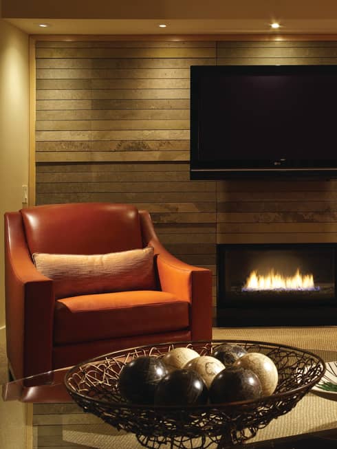 Red armchair beside gas fireplace, TV mounted on wall