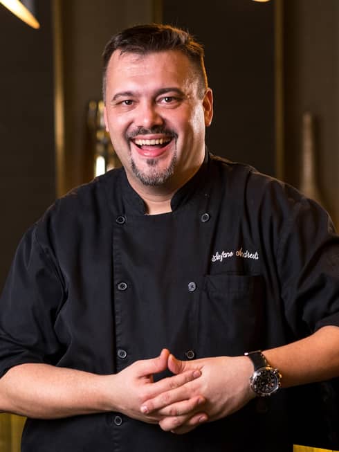 Chef Stefano wearing a black Four Seasons uniform and smiling.