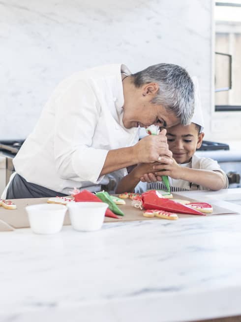 A chef and child decorating cookies.