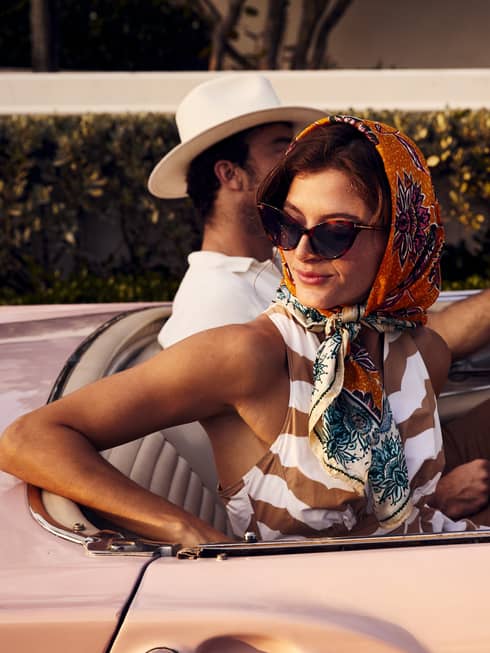 A woman in a scarf and a man in a hat in an old vintage car.