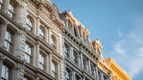 Close-up of ornate historic building facade with arched windows and decorative columns under a clear blue sky