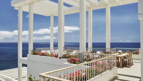 Penthouse Suite patio tables, chairs under white pergola, tropical pink flowers