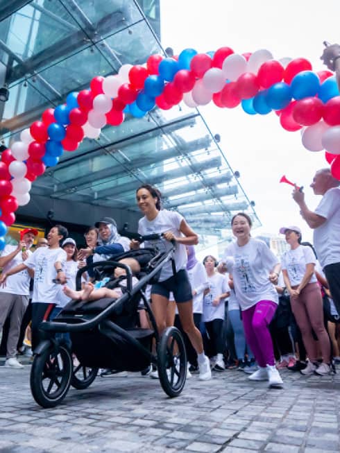 Terry Fox run in Kuala Lumpur, featuring a woman with running stroller passing a balloon-arched finish line