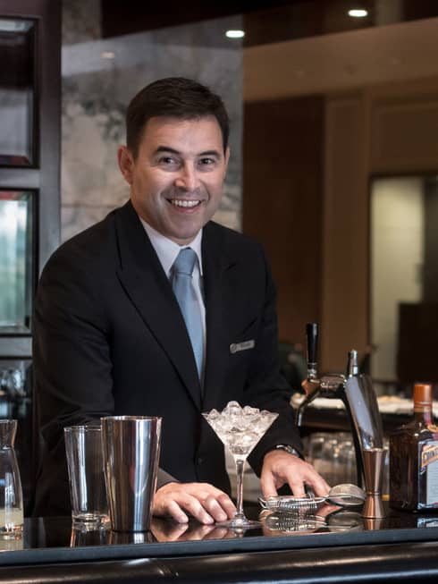 Portrait photo of Ritz Bar manager Ricardo Felgueiras in suit in front of martini glass, shaker