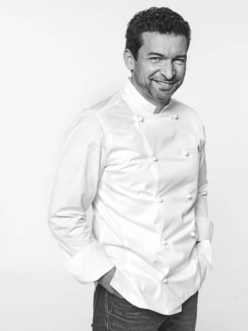 Guillaume Cabrol in white chef's coat, hands in pockets, smiling