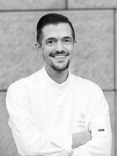 Executive Sous Chef Nicholas Trosien in white chef?s coat, smiling and standing with arms folded