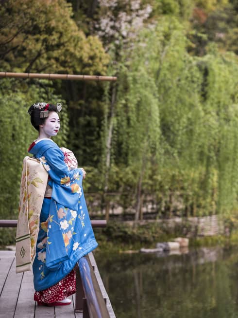 A geisha stands on the dock of the yoga barn and overlooks the serene lake