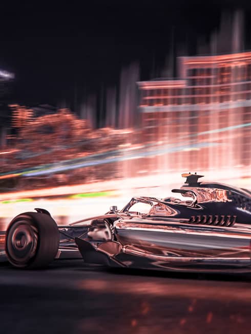 A race car driving quickly near a building.