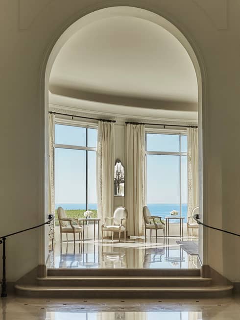 Tall arched doorway leading to dining tables, chairs under sunny windows in Rotunda