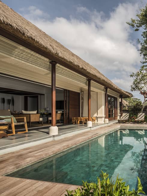 Villa patio with rectangular swimming pool, thatched roof over shaded seating area