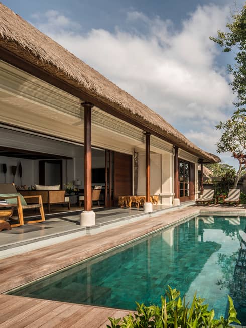 Villa patio with rectangular swimming pool, thatched roof over shaded seating area